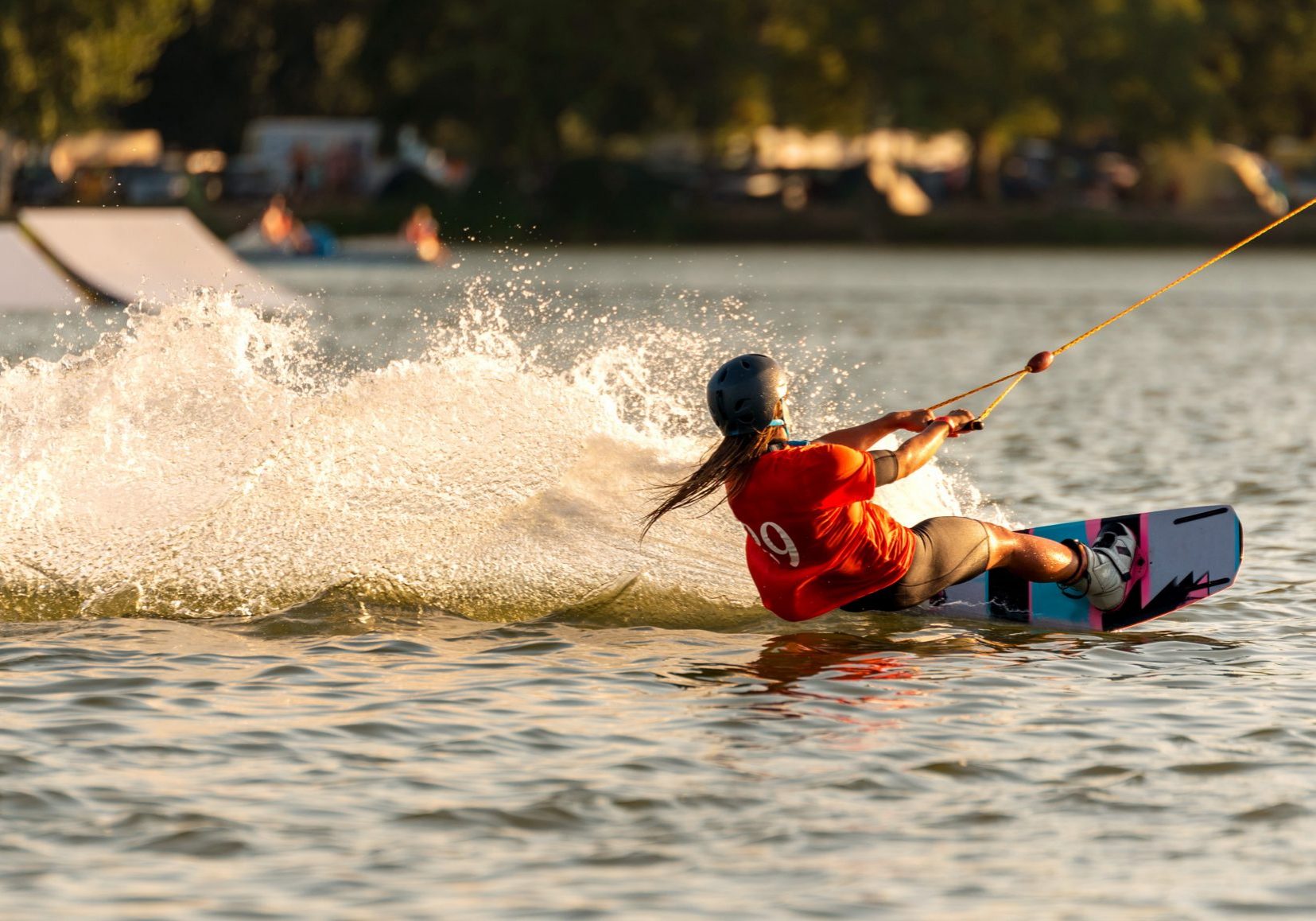 Young active woman on the wakeboard in cable park
